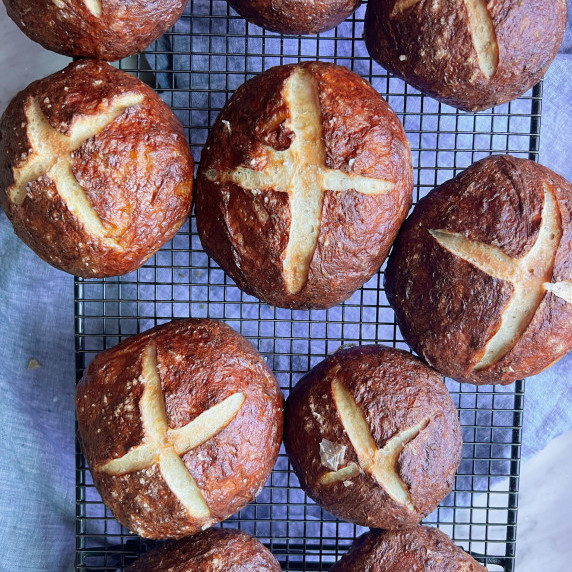 German pretzel rolls on a wire rack over a blue napkin.