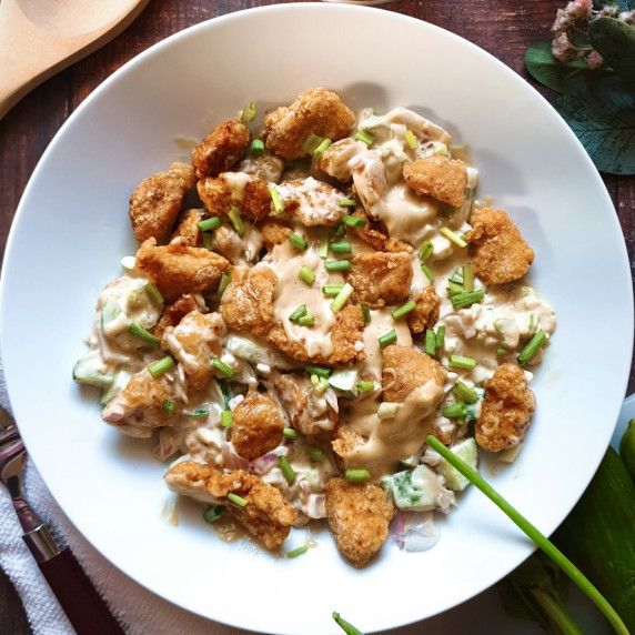 Gluten free chicken salad in a large white bowl garnished with chopped green onion.