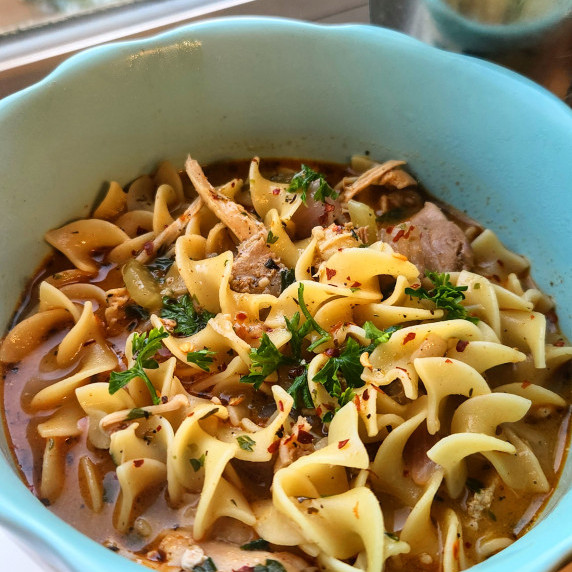 A blue bowl filled with paprikash noodle soup with chicken