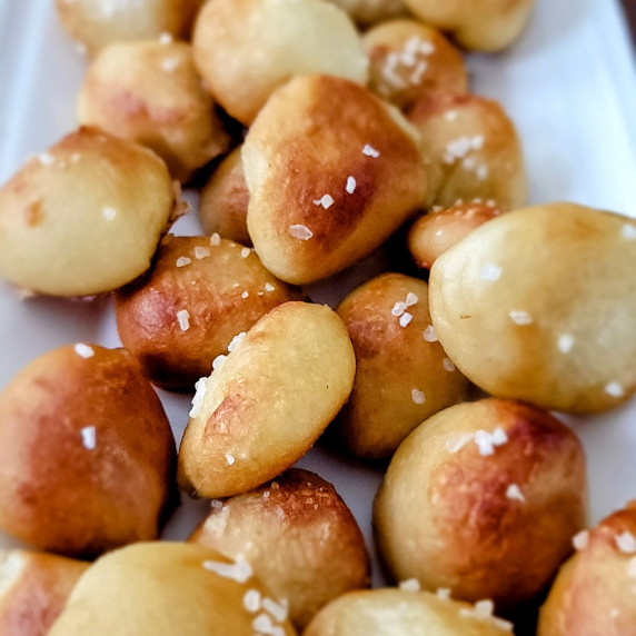 A white platter piled with salted, baked pretzel bites.