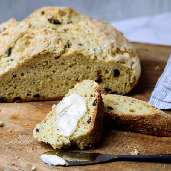 Loaf of Irish Soda Bread with a slice slathered with butter.