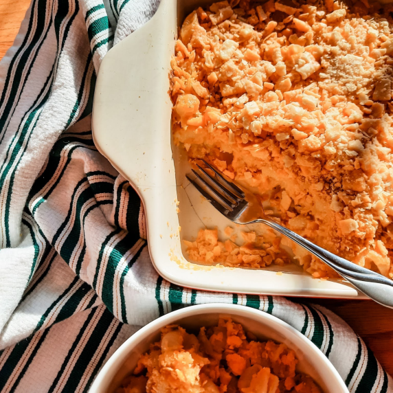 Pan of Cheez-It Mac & Cheese next to a bowl of mac & cheese and a striped tea towel.
