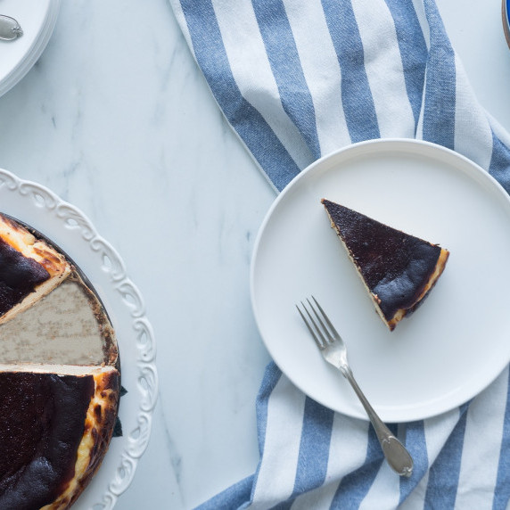 This picture features a piece of the The Basque Burnt Cheesecake on a plate with a fork and the cake