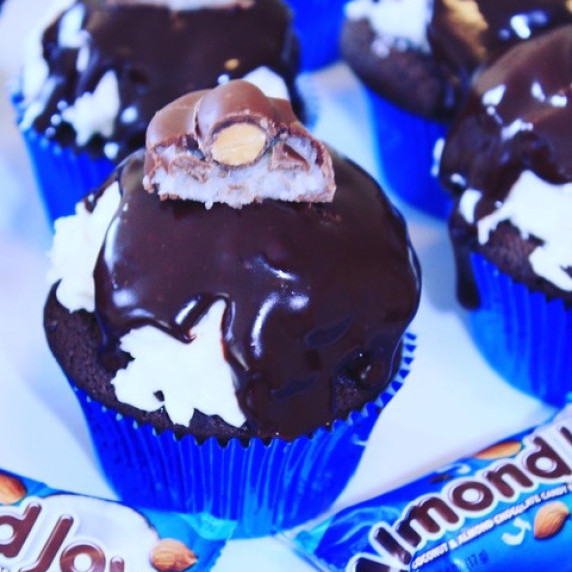 Almond Joy Cupcakes topped with mini-almond joy candies on a white tablecloth.