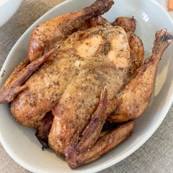 whole golden chicken on white platter