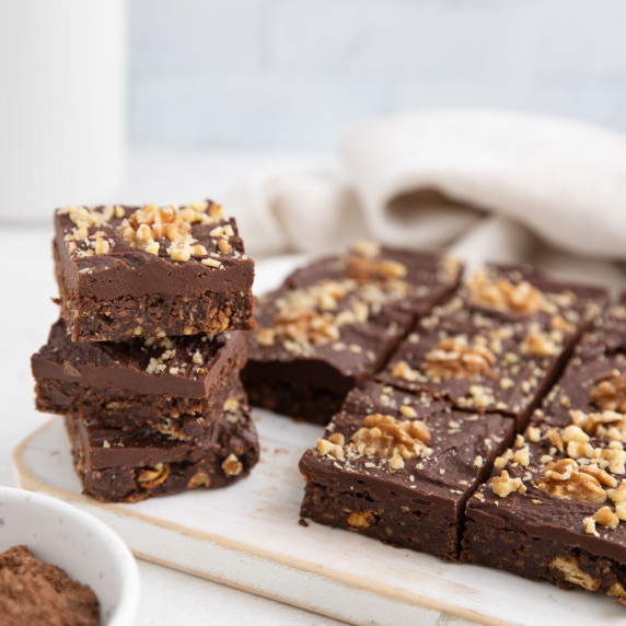 A stack of chocolate biscuit slices on a wooden chopping board