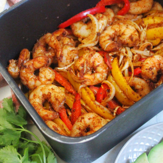 Shrimp fajitas in black air fryer basket. 
