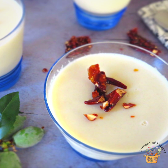 White almond pudding in a clear glass with praline on a gray board