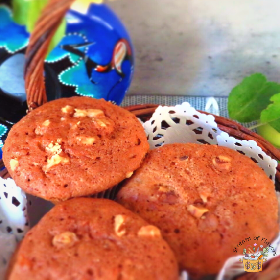Apple muffins with oil topped with walnuts in a basket with a vase of rose on a gray board
