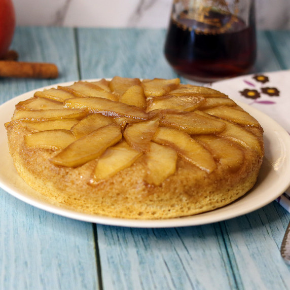 Upside Down Apple Soufflé Pancake on a white plate with syrup in the background