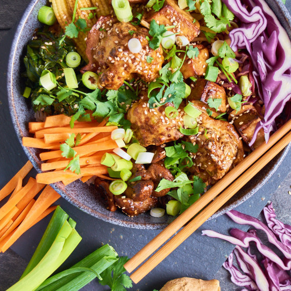 A bowl of Asian Bowl with Cauliflower and Tofu with red cabbage, carrots, mini sweetcorn, soy sprout