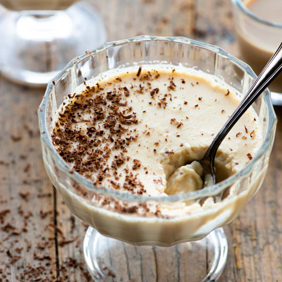 A bailey's panna cotta in a small glass serving dish with a spoon