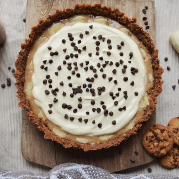 Banoffee pie with banana, arequipe, chocolate chip cookies and chocolate chips on a table. 