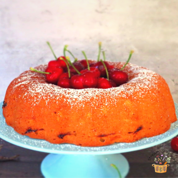 Basque ring cake with cherries in the middle on a blue cake stand