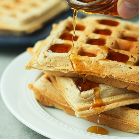 two vegan belgian waffles stacked on a white plate