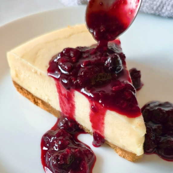 Berry Sauce Recipe drizzled over a cheesecake slice.