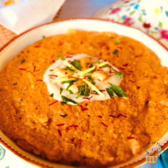 Butter chicken topped with creamy cashew sauce, cilantro, and saffron in a tureen
