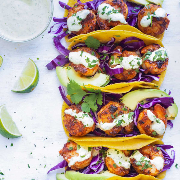 Easy Blackened Shrimp Tacos RECIPE served next to crema and limes.