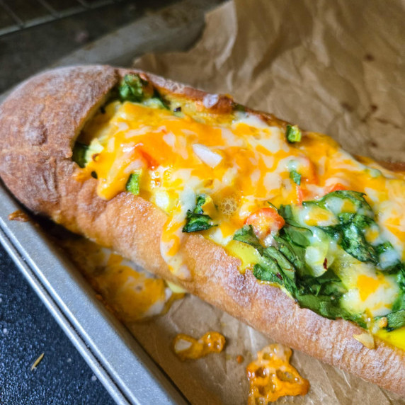 Golden baguette stuffed and topped with melty, golden cheese and green spinach.