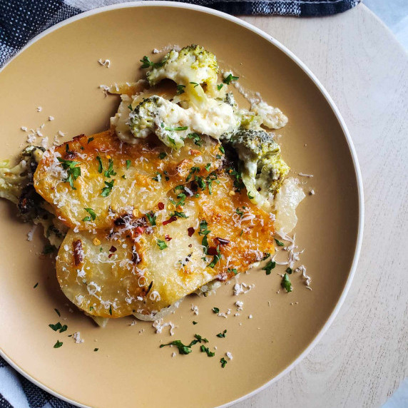 Golden brown crusted potatoes in a creamy white sauce on a beige plate.