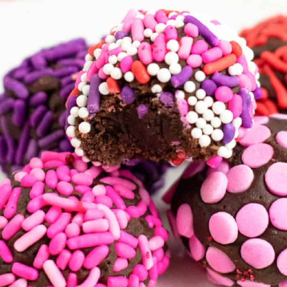 Close up of brownie truffles in a small stack with one missing a bite. 