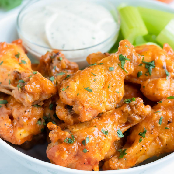 Baked Buffalo Chicken Wings RECIPE served on a white platter with ranch and celery on the side.