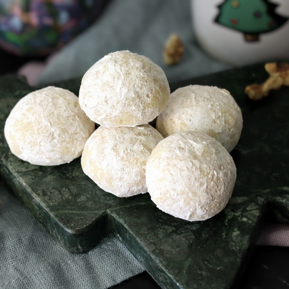 a handful of butter ball cookies arranged on a Christmas tree platter