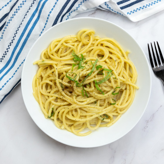 Top down shot of vegan butter noodles with a tea towel and fork next to the bowl