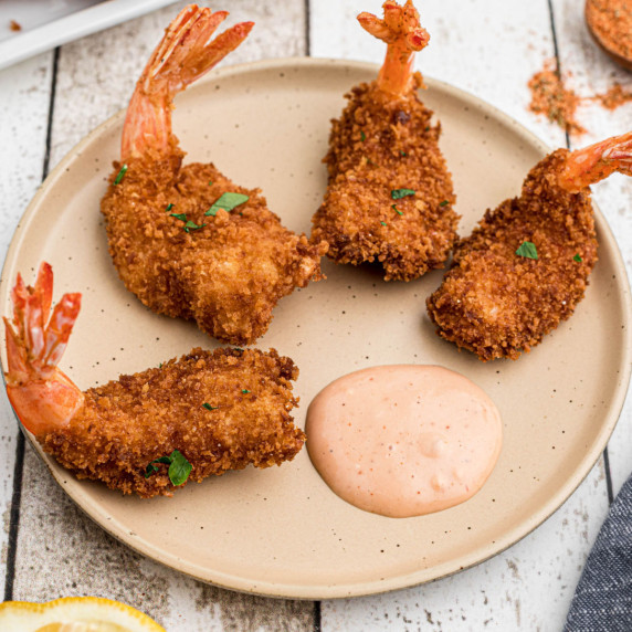 A circle of butterfly shrimp around some tasty dip.