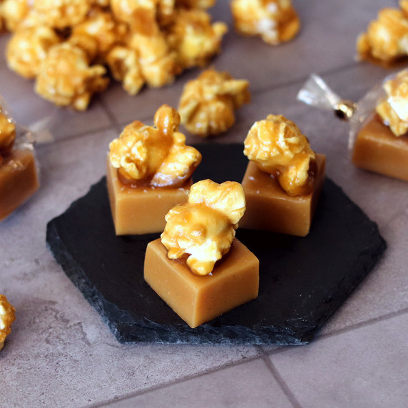Three caramel corn caramels arranged on a small black board on a tiled counter.