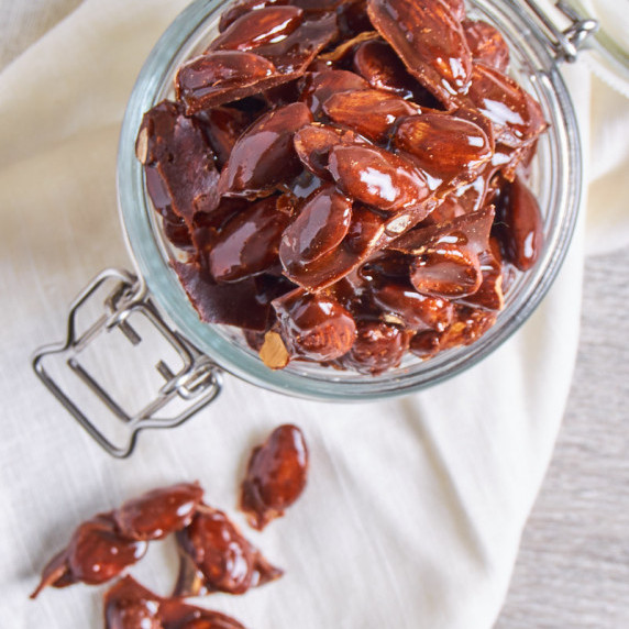 A jar of Caramelized Spiced Almonds, shiny and dark