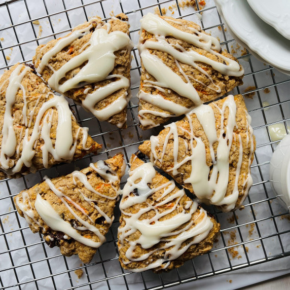 Six scones on a wire rack topped with a white glaze. 