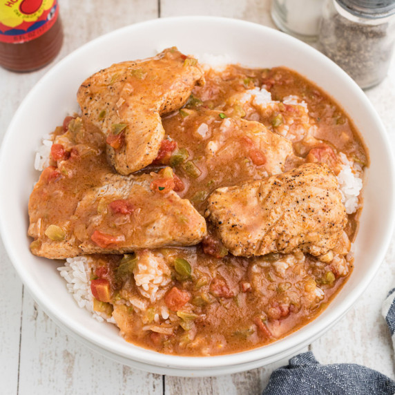 View of a bowl of catfish courtbouillon on top of a bed of rice.