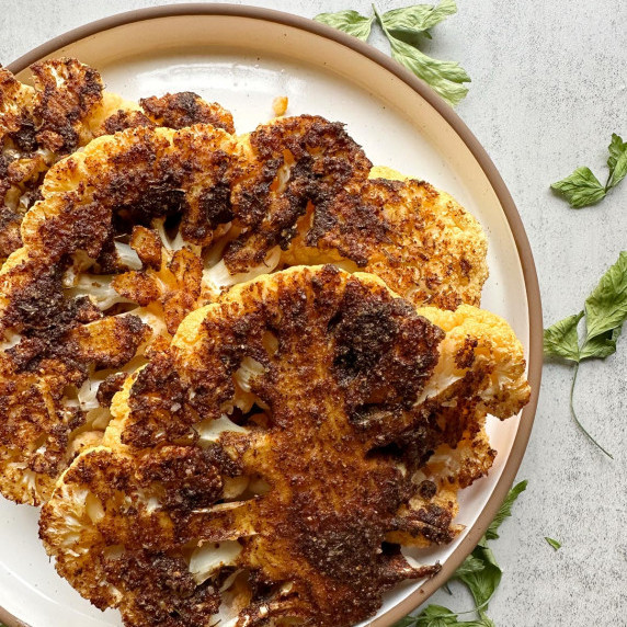 finished cauliflower steaks on a white plate