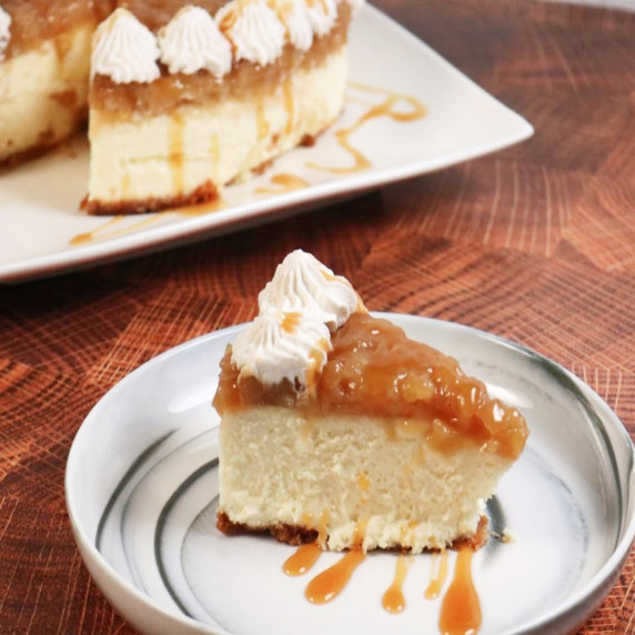 Slice of Cheesecake with Apple Pie Topping on a plate with whole cheesecake in background