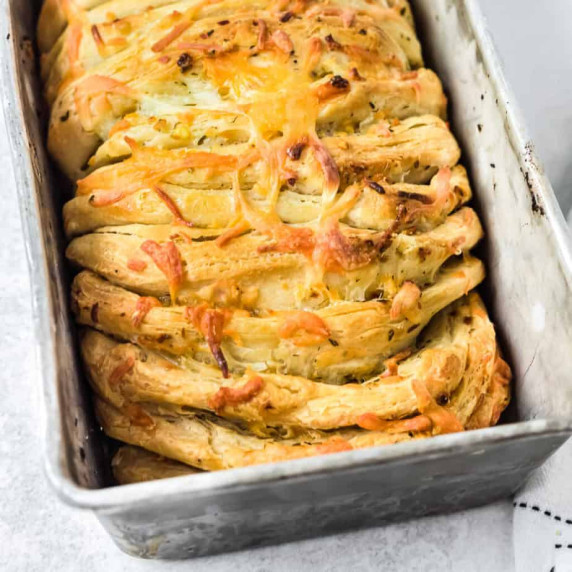 Cheesy bread in loaf pan tilted zoomed in on end of pan.