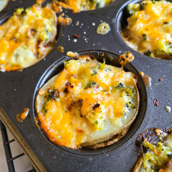 A muffin tin full of cheesy, golden au gratin bites.