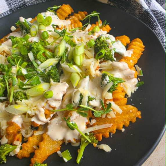 Golden fries smothered in white queso with pops of green from broccoli and onions.