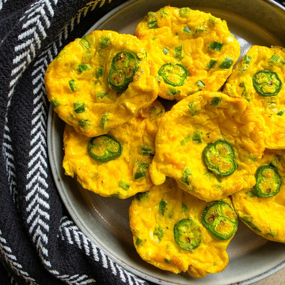 Golden mini frittatas with green jalapenos against a black towel