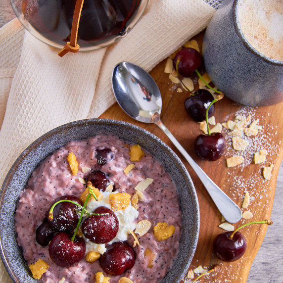 A bowl of Cherry Bakewell Protein Oats, topped with fresh cherries, marzipan and greek yoghurt.