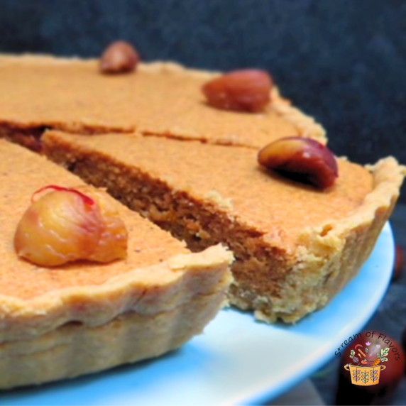 Chestnut tart with roasted chestnuts and cardamom and saffron strands on a blue stand
