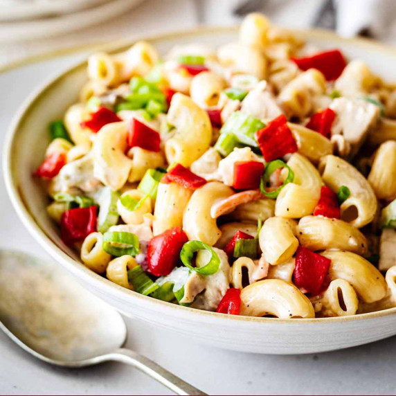 Chicken macaroni salad in a white bowl with a serving spoon