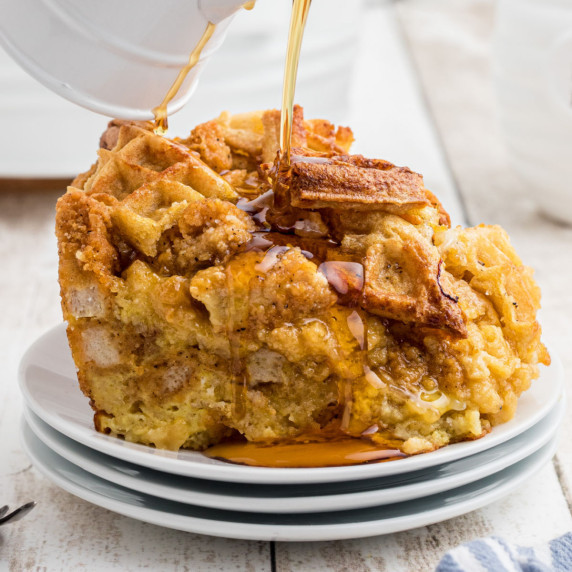 Close up of some chicken and waffle casserole with syrup being drizzled over.