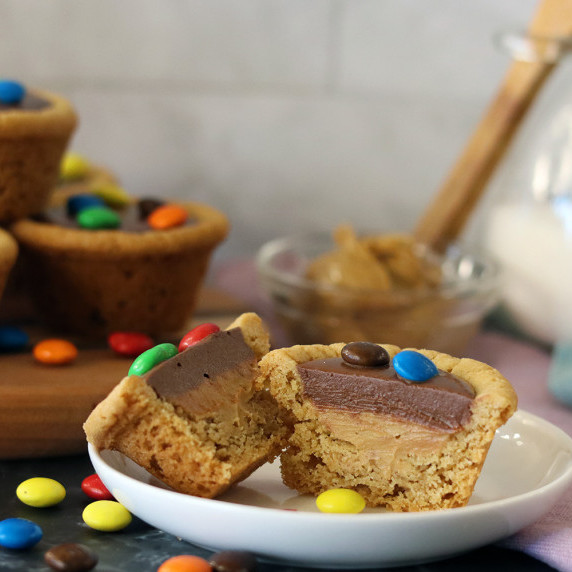 A choco peanut butter cup cut open to show the layers of filling, more cups in the background