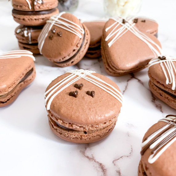 Chocolate almond macarons with white chocolate drizzle and dark chocolate piped hearts