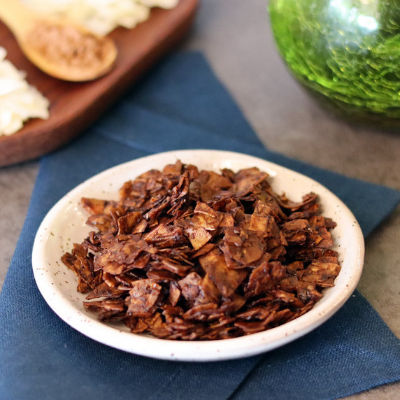Chocolate coconut chips in a small bowl on a blue napkin.