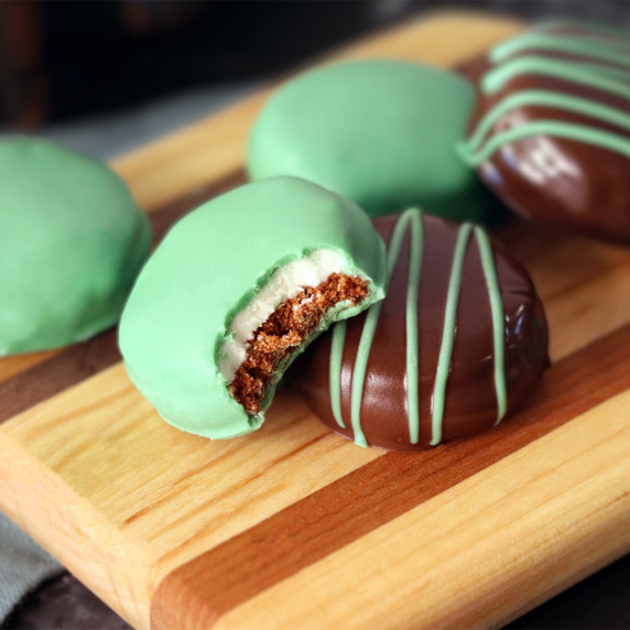 Chocolate mint surprise cookies on a wooden board, one with a bite taken from it.
