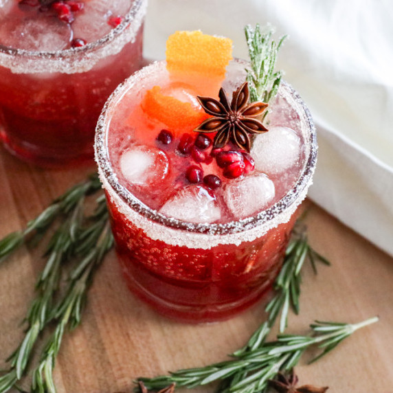 cranberry pomegranate christmas mocktail with orange, lime, cinnamon, star anise, and rosemary.