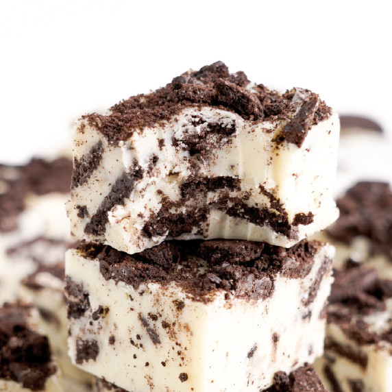 Two pieces of white chocolate fudge mixed with chocolate Oreo cookies. Top piece missing a bite.