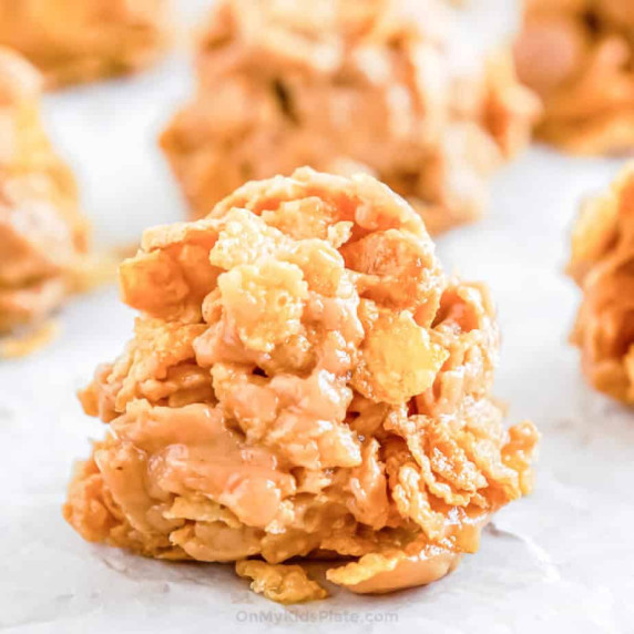 Close up of cornflake no bake cookies on parchment with other cookies in the background.